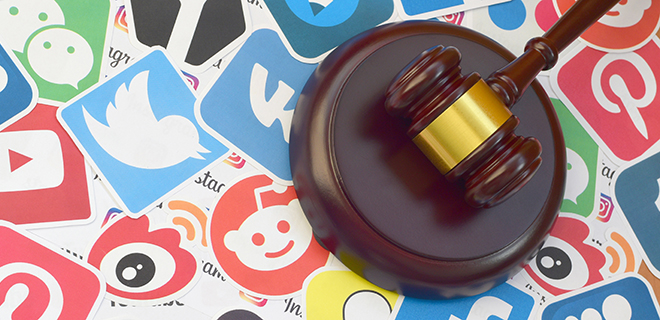 KHARKOV, UKRAINE - FEBRUARY 17, 2020: Wooden judge gavel lies on many paper logos of popular social networks and internet resources. Entertainment lawsuit concept
